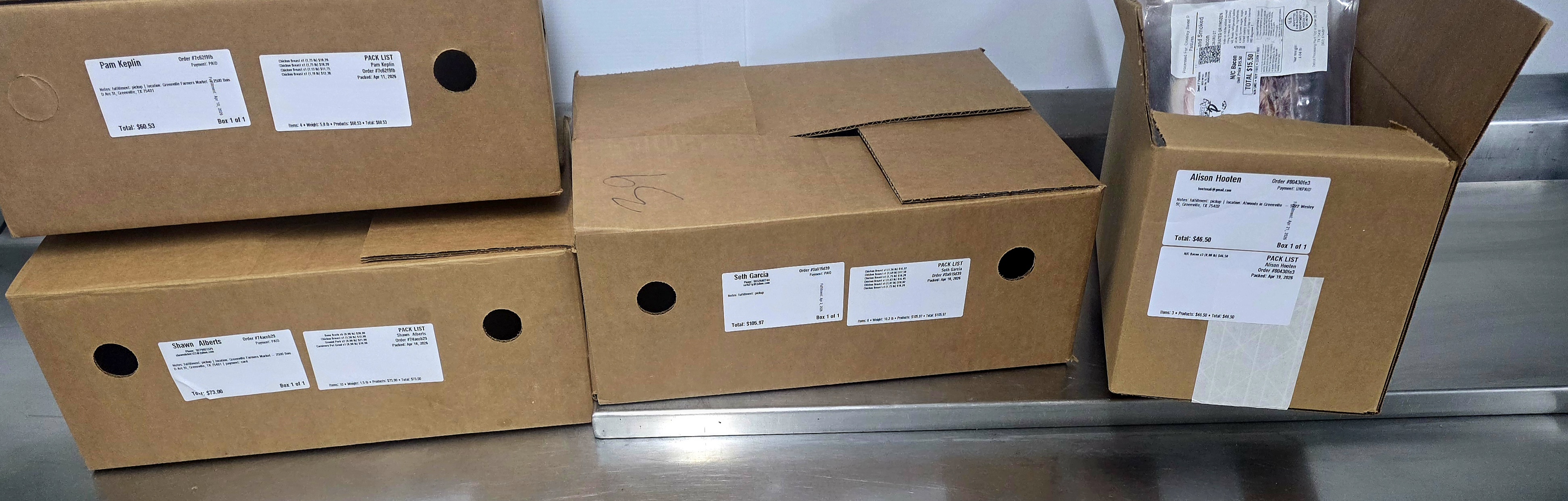 PurveyOS fulfillment photo showing printed pack lists and box labels laid out for customer order verification and pickup organization.